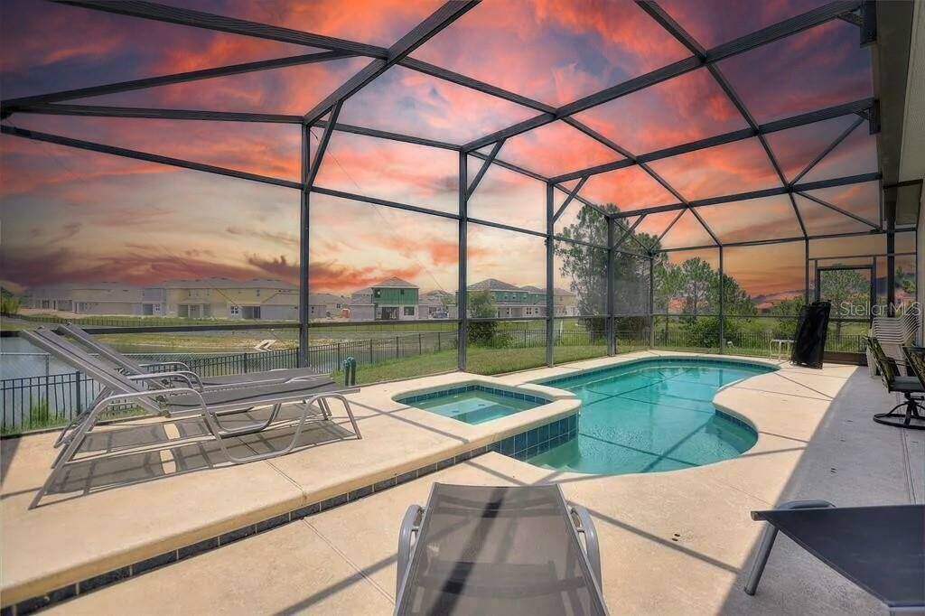Piscina techada al aire libre con vista a un atardecer y edificios lejanos.