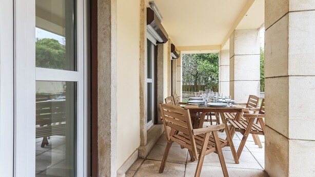 A covered outdoor dining area with a table set for four, surrounded by wooden chairs. - Belem Boutique II by Homing (Lisbon)