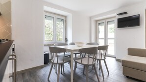 A modern kitchen with a dining table and chairs, large windows, and a TV mounted on the wall. - Belem Boutique II by Homing (Lisbon)