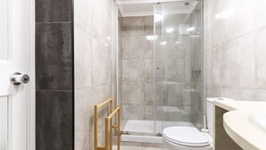 A modern bathroom with a glass-enclosed shower, a white toilet, and a beige sink. - Belem Boutique II by Homing (Lisbon)