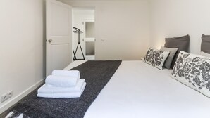A bedroom with a bed, a bedside table, a lamp, and a door leading to a bathroom. - Belem Boutique III by Homing (Lisbon)