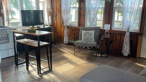 Interior acogedor de una cabaña con suelo de madera, una mesa de comedor con sillas, un sofá y un televisor.
