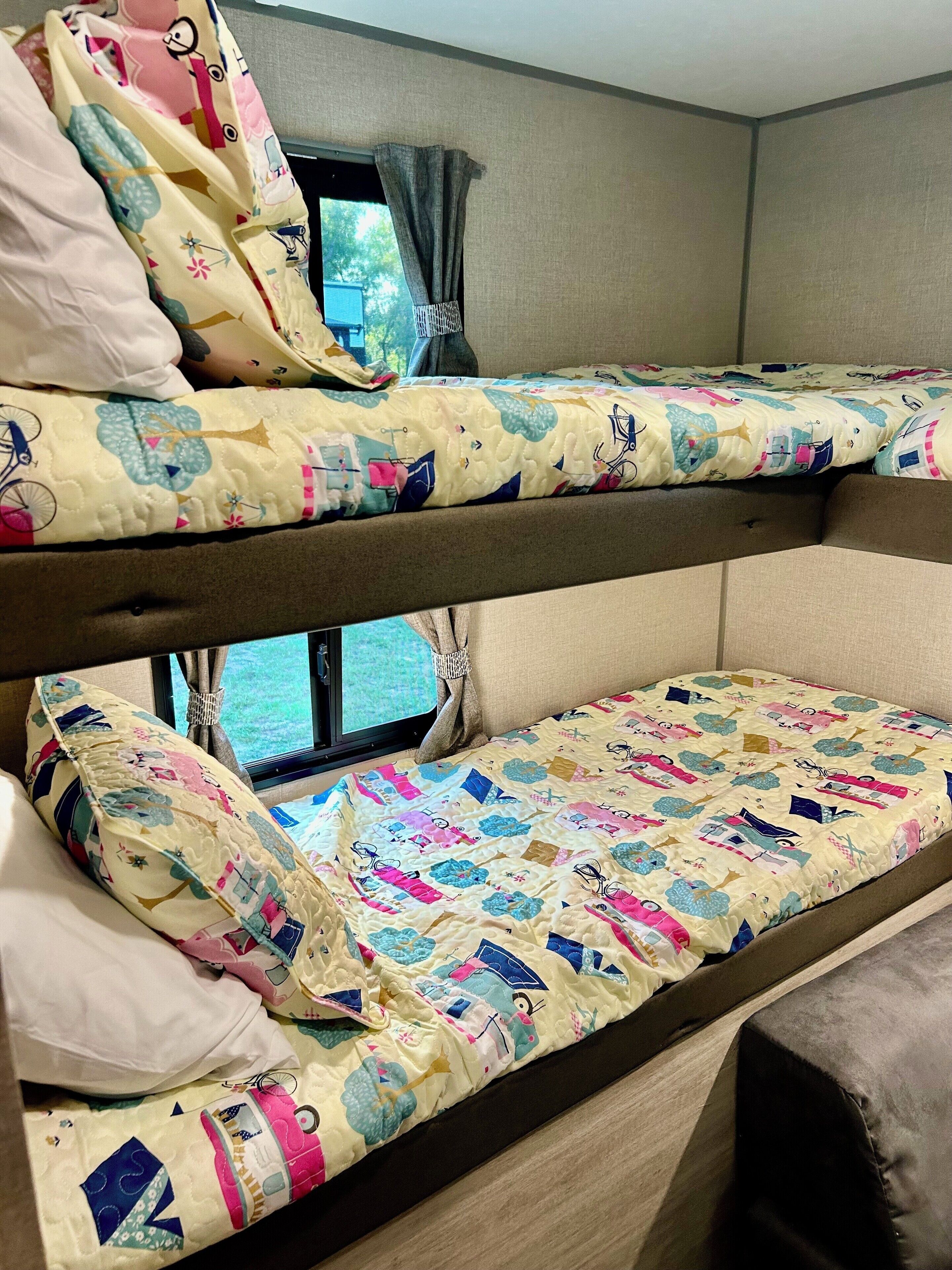 A bunk bed with colorful bedding and a window with curtains.