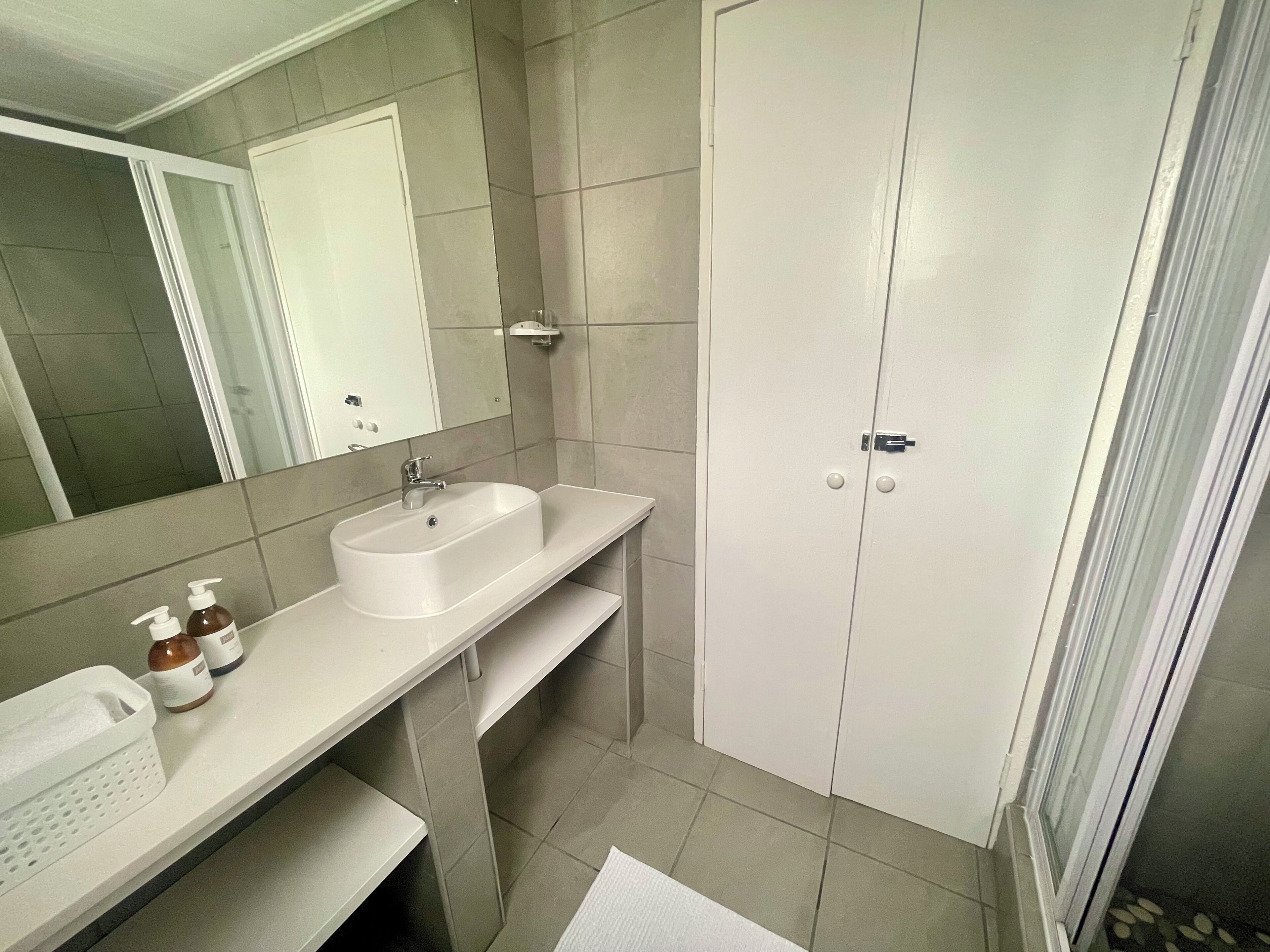 A bathroom with a white sink, mirror, and two doors.