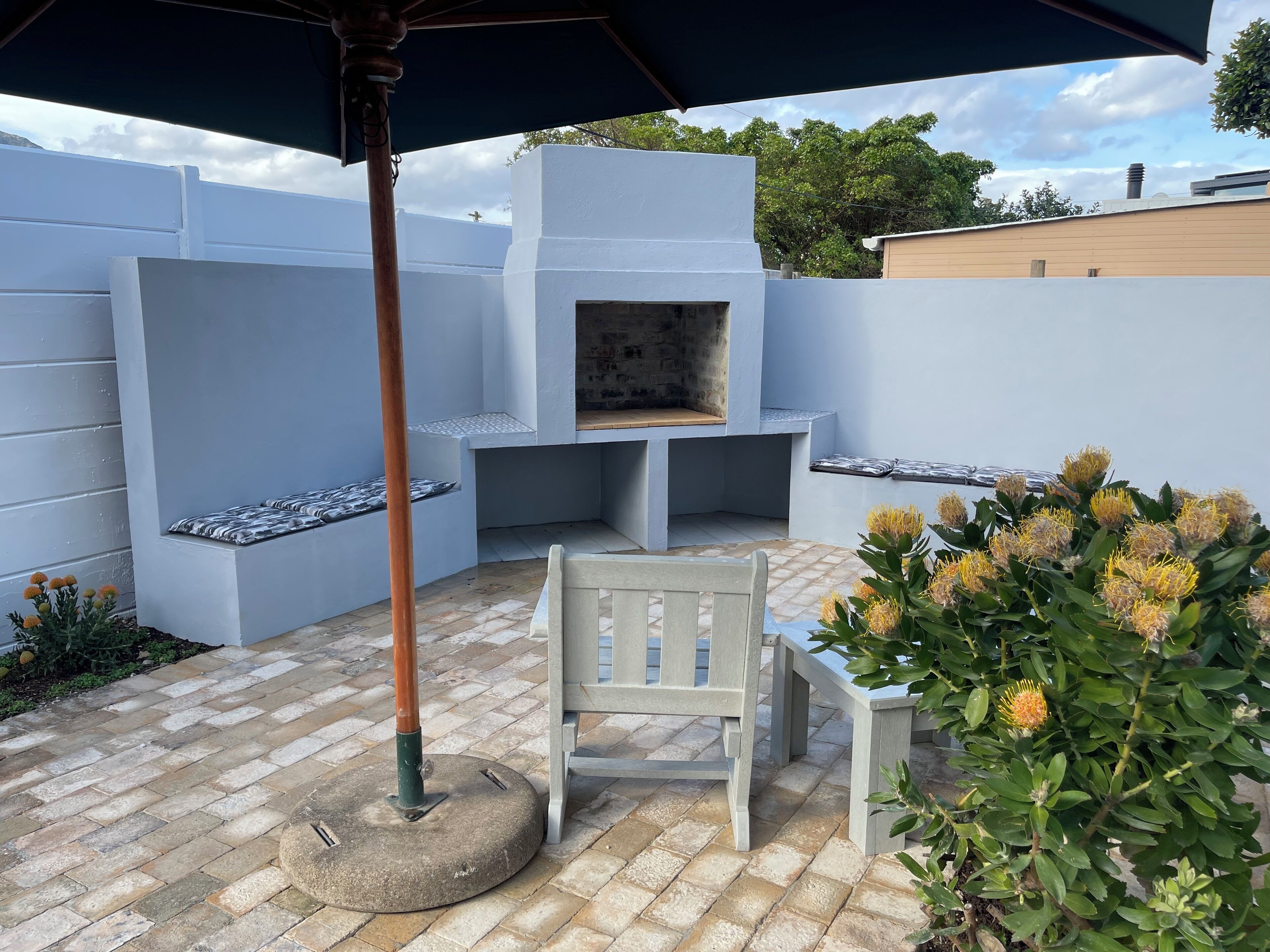 A patio area with a built-in grill, seating, and a potted plant.