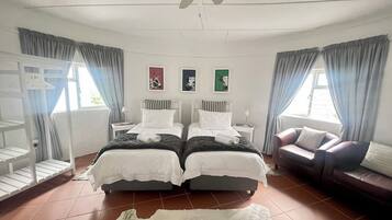 A hotel room with two beds, a ceiling fan, a sofa, and artwork on the walls.