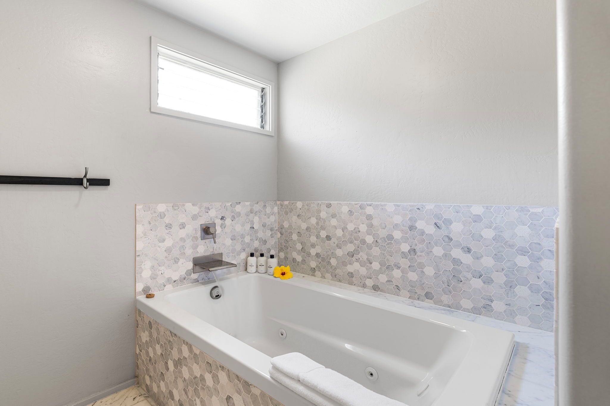 Un baño con una bañera blanca, una ventana y un salpicadero de azulejos.
