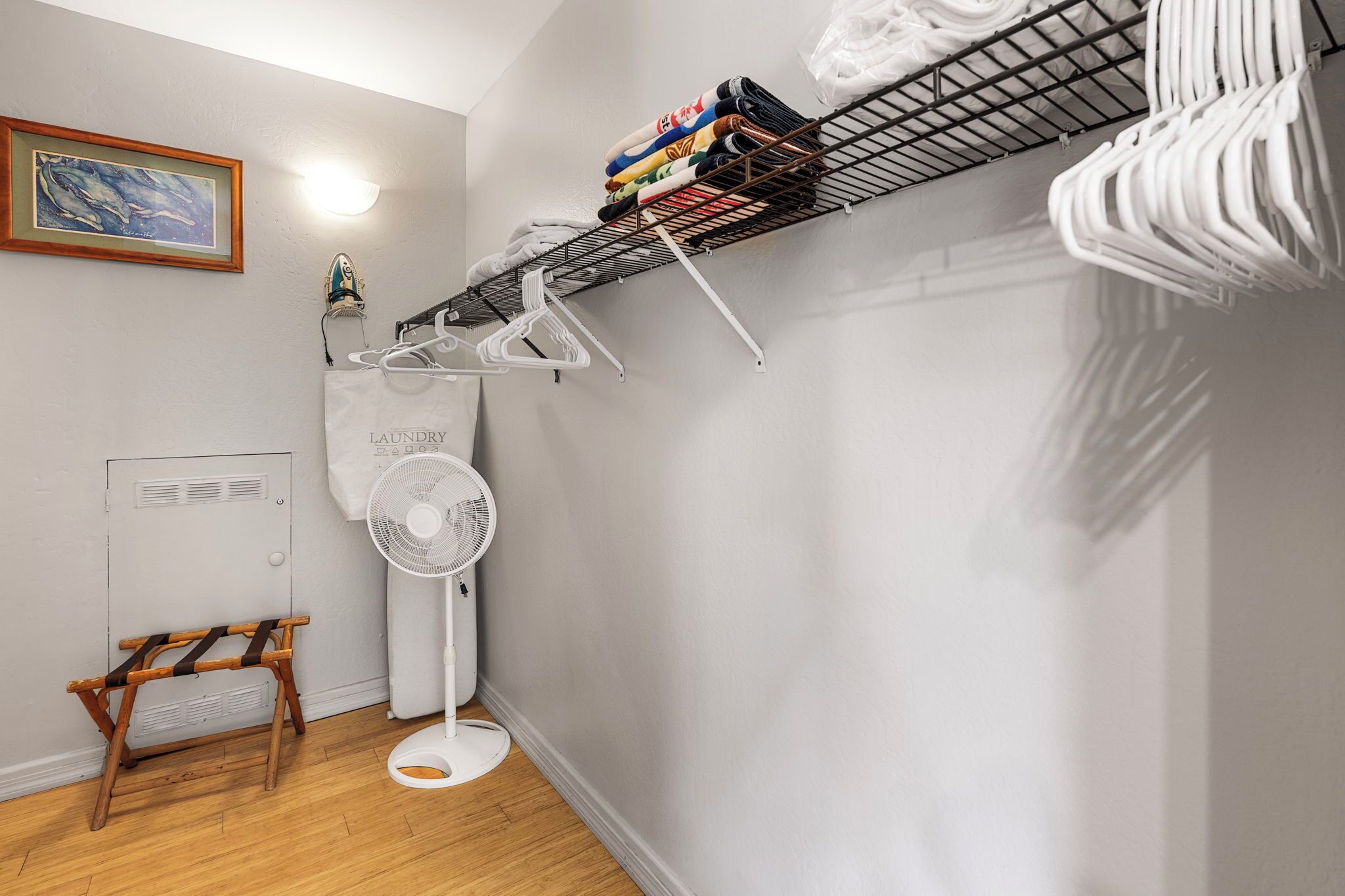 A laundry area with a drying rack, a fan, and a wooden rack.