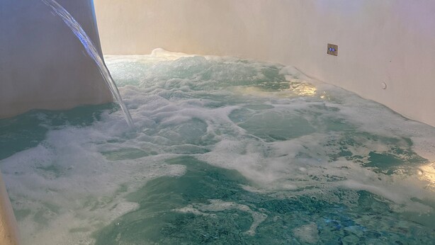 Interior de un hotel de hielo con techos abovedados y una fuente central de agua.