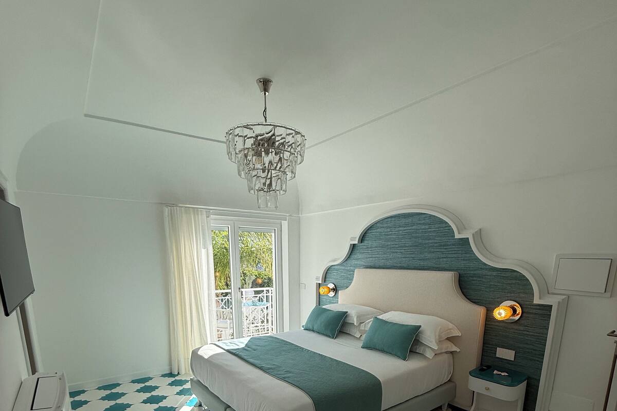 Een moderne slaapkamer met een groot bed, een kroonluchter en een vloer met een patroon.