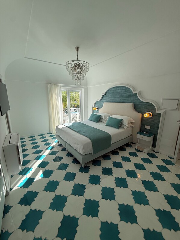 A modern bedroom with a large bed, a chandelier, and a patterned floor. - Lussi Capri Boutique Hotel (Anacapri)