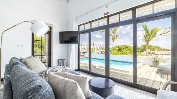 A modern living room with a large window, a pool, and a sofa.