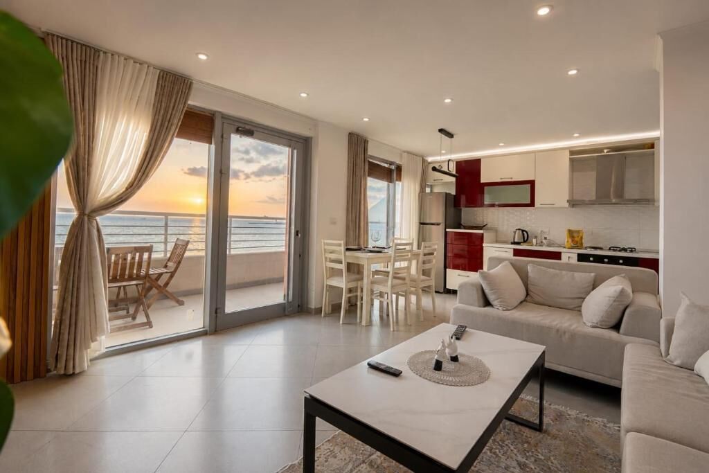A modern living room with a balcony, a dining area, and a kitchen.