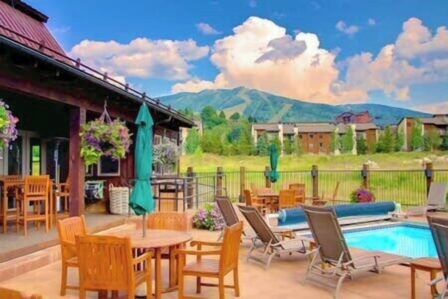 Un espace piscine aménagé avec des chaises longues et une table, entouré d’une terrasse en bois et d’un patio couvert.