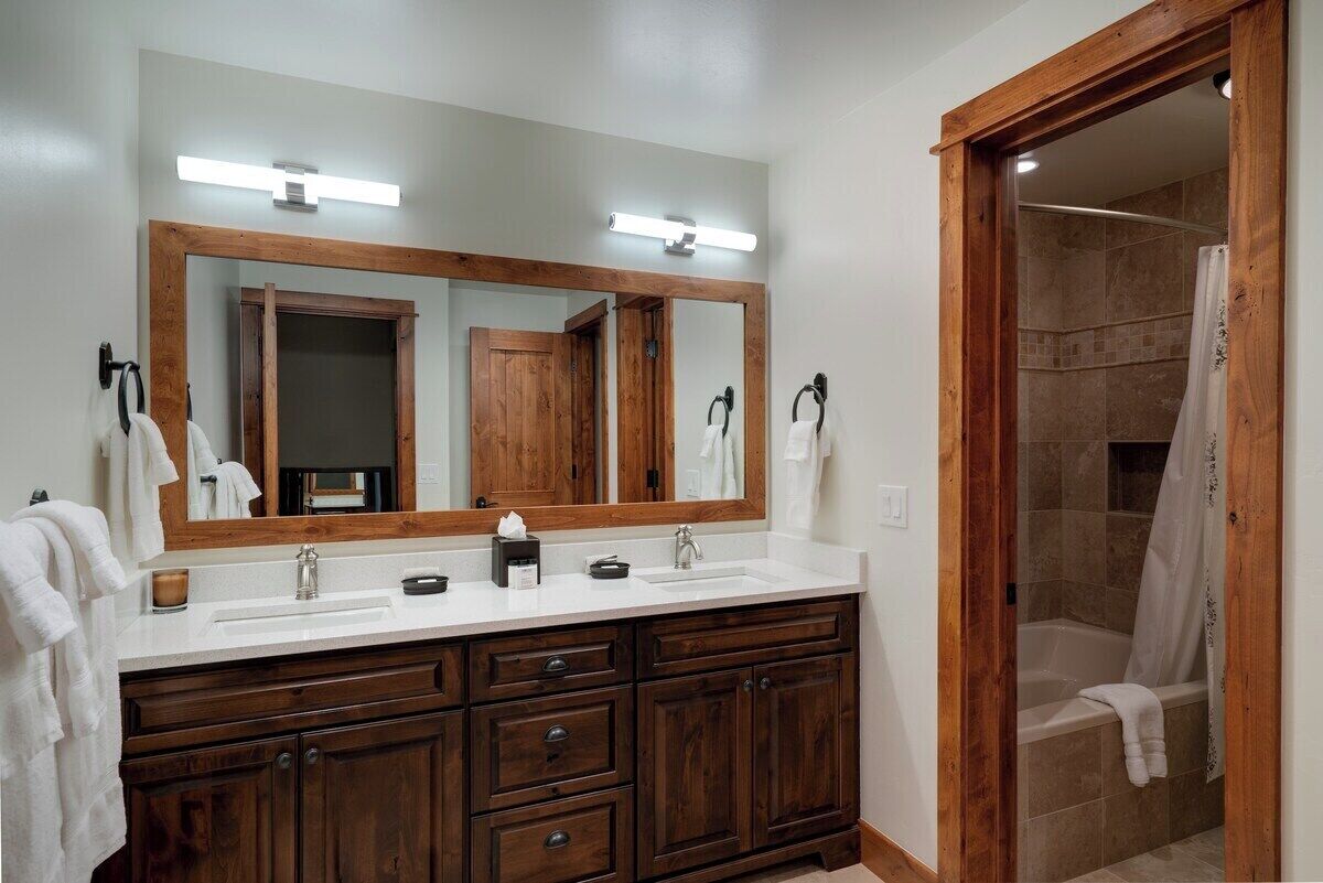 Une salle de bain avec un meuble-lavabo en bois, un grand miroir, un espace douche et une baignoire.