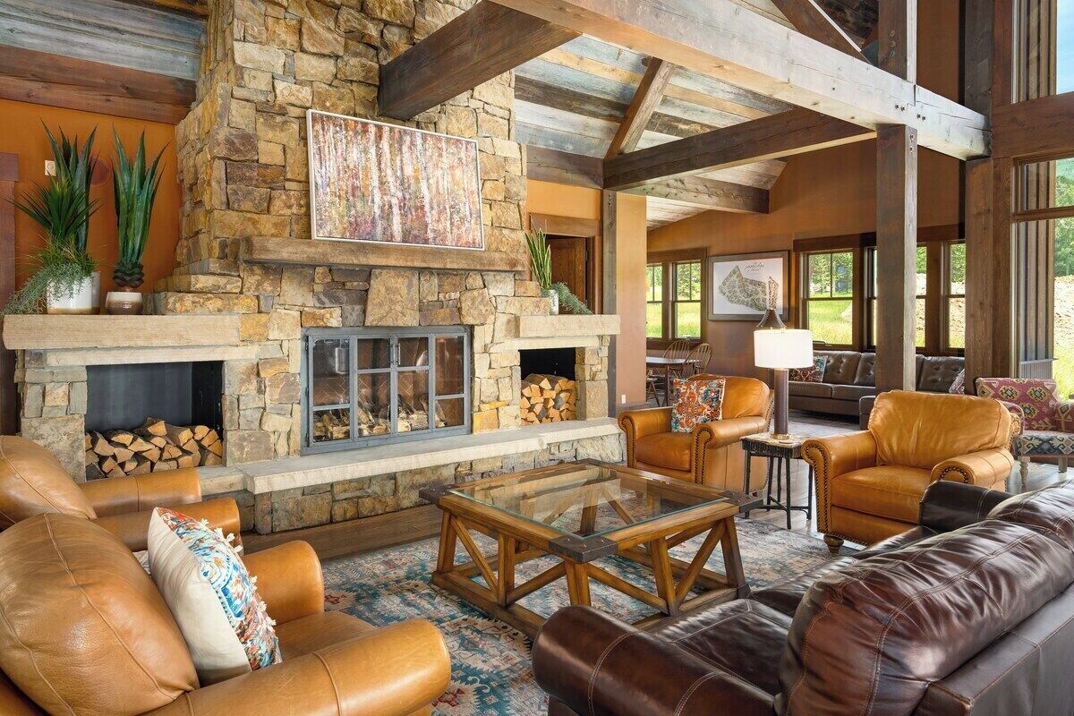 A spacious living area with a stone fireplace, leather sofas, and a glass coffee table.