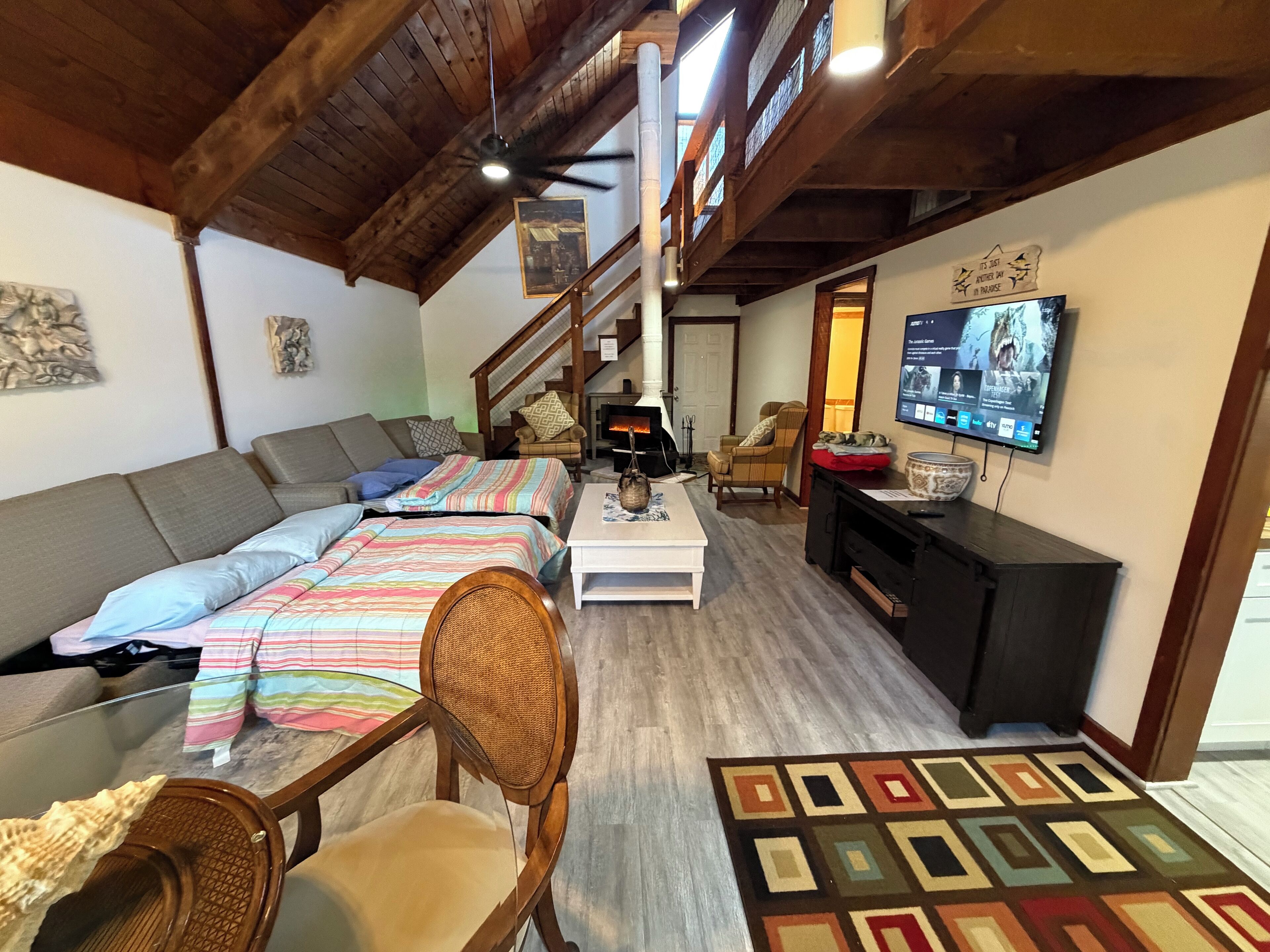 Una sala de estar acogedora con techo de madera, un sofá, una mesita de centro, un televisor y una chimenea.