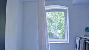 A bathroom with a bathtub, a window, and a bench. - Vacation apartment in the Allgäu (Aichstetten)