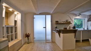 A modern kitchen with wooden flooring, white cabinetry, and a central island. - Vacation apartment in the Allgäu (Aichstetten)