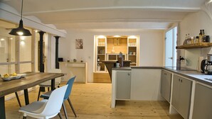 A modern kitchen with wooden flooring, a dining area with a wooden table and chairs, and built-in cabinets. - Vacation apartment in the Allgäu (Aichstetten)