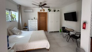 A bedroom with a bed, a desk, a chair, a TV, and a wardrobe.