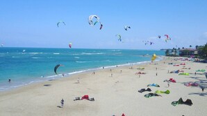 A beach with people, kites, and a clear sky.