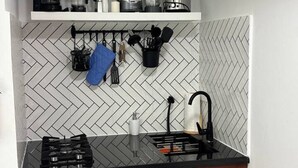A kitchen with a black countertop, a gas stove, a sink, and a herringbone-patterned backsplash.