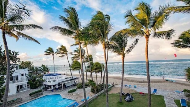 Un complexe hôtelier doté d’une piscine, de palmiers et offrant une vue sur la plage.