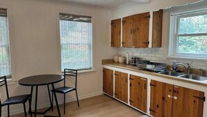 A kitchen with wooden cabinets, a sink, and a dining table with chairs.