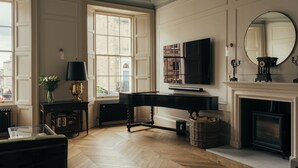 A room with a piano, a fireplace, a television, and a large window.