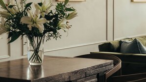 A dining area with a wooden table, chairs, and a vase of flowers.