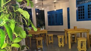 A room with a wooden table and benches, a potted plant, and blue-framed windows. - Hiriketiya Hideway  (Hiriketiya)
