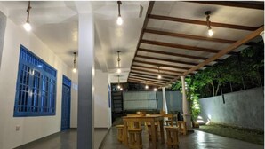 A corridor with blue-framed windows, a wooden ceiling, and a dining area with tables and chairs. - Hiriketiya Hideway  (Hiriketiya)