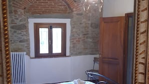 A bedroom with a bed, a window, a stone wall, and a wooden door. - Tuscan Villa 15 min from Florence, Parking, Garden (Pian di Mugnone)