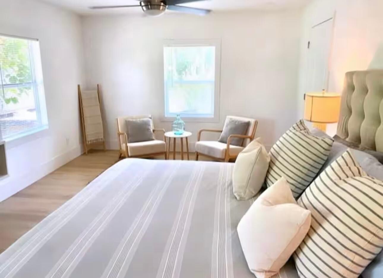 Ein Schlafzimmer mit einem großen Bett, zwei Sesseln, einem kleinen Tisch und einem Deckenventilator.