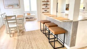 A modern kitchen with a central island, bar stools, and a dining area with chairs. - Pet-Friendly Estero Spacious House • Near FGCU, Beaches, RSW Airport & Hertz (Fort Myers)