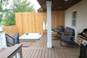En træterrasse med jacuzzi, udendørs møbler og grill.