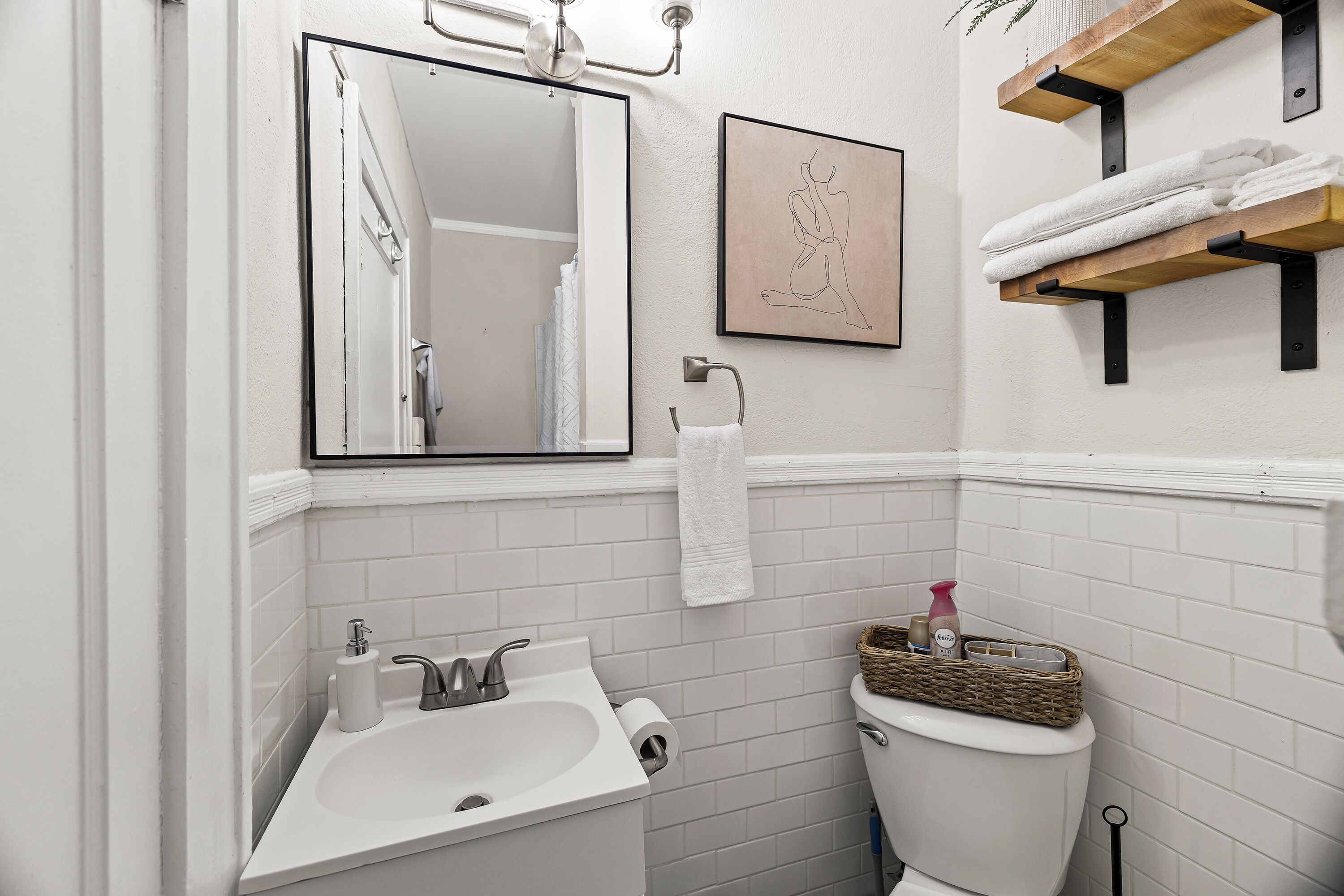 Une salle de bain avec un lavabo blanc, un miroir, des toilettes et un porte-serviettes.