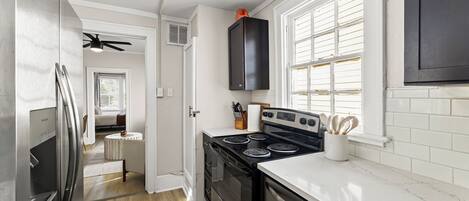 A compact kitchen with a refrigerator, stove, oven, and a microwave.