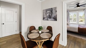 Ein Essbereich mit einem runden Tisch, vier Stühlen und einem Buddha-Gemälde an der Wand.