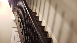 Una escalera de madera con barandilla oscura y paredes blancas.