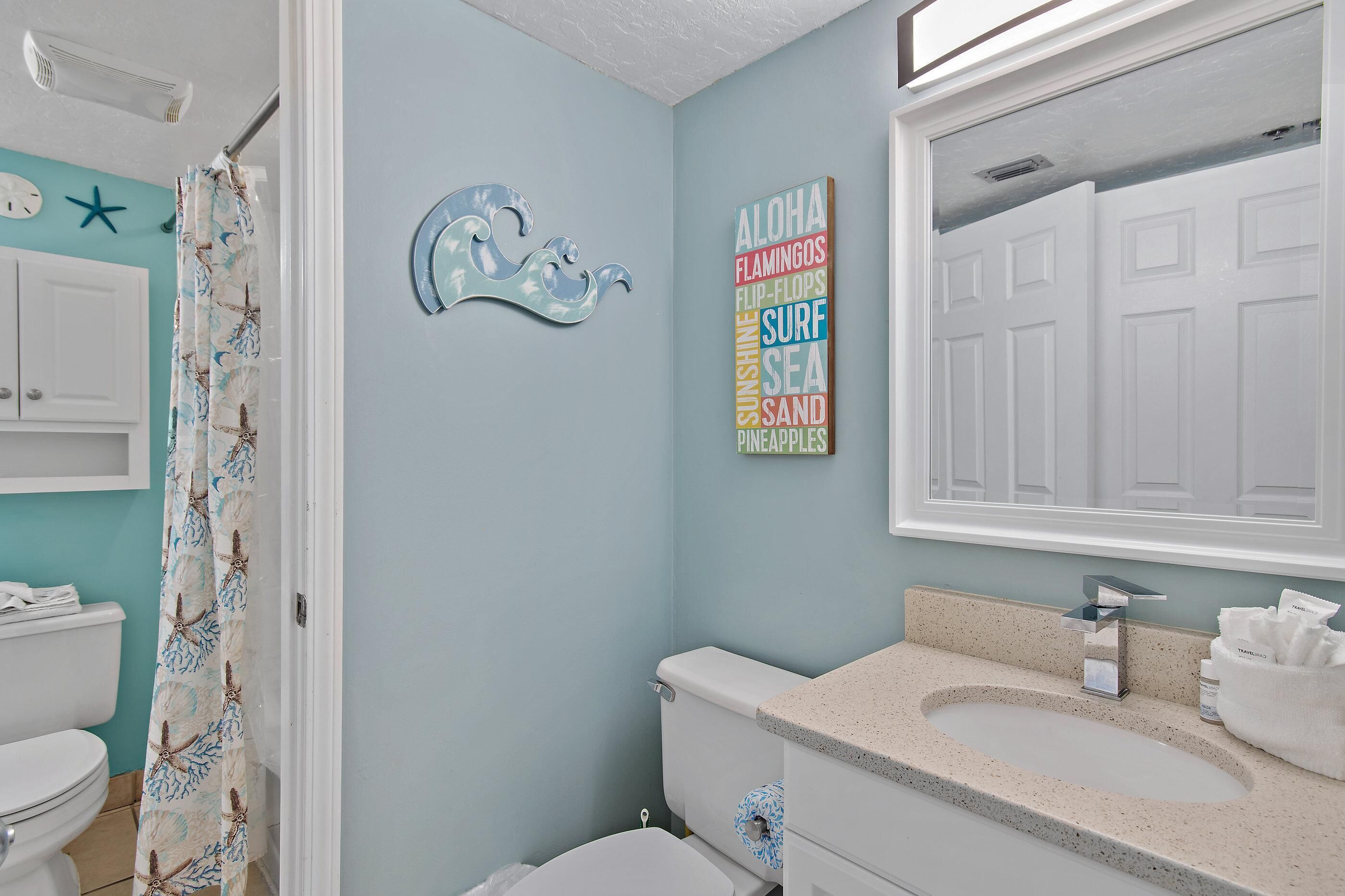 A bathroom with a toilet, sink, and shower curtain.