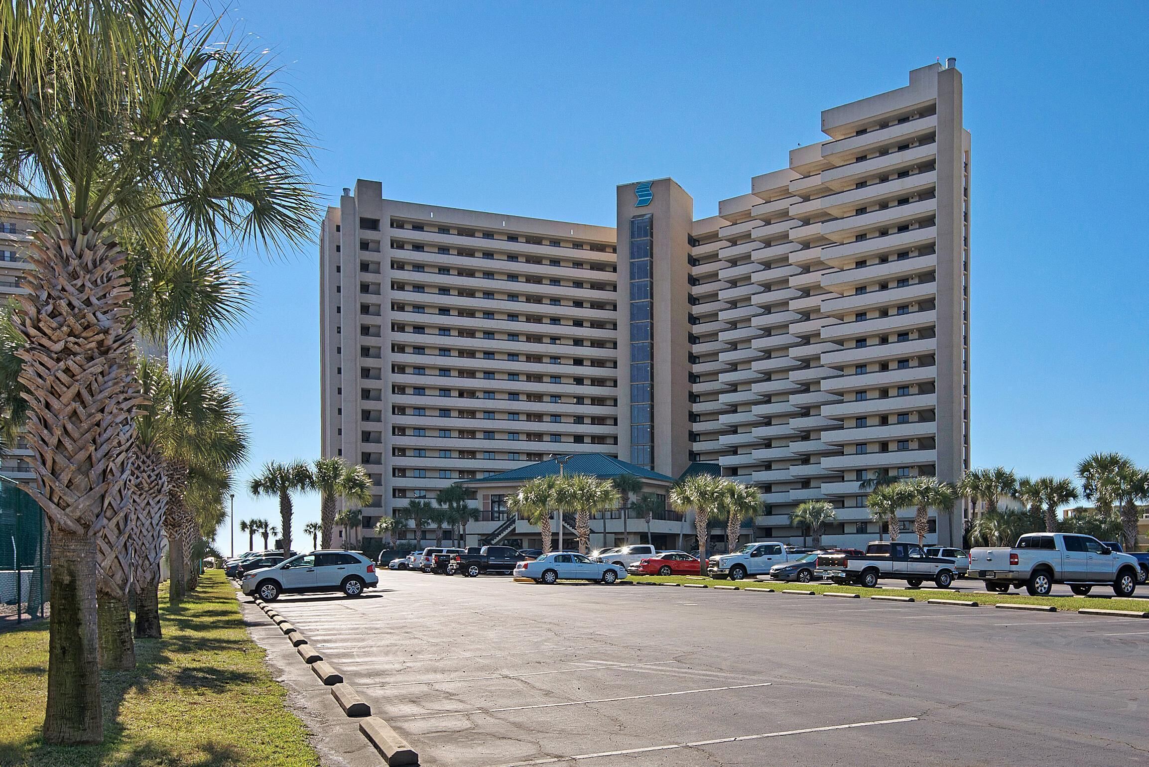 A multi-story hotel with a modern architectural design, featuring a prominent vertical tower and a series of balconies.