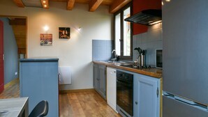 Eine Küche mit Holzbalken, einem Geschirrspüler, einem Backofen und einem Kühlschrank.
