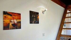 A room with a wooden ceiling, a white wall, and two artworks depicting wine and a barrel. - Chez Fred 201 – Parking, Wi-Fi, Near Savoie College (Saint-Pierre-d'Albigny)
