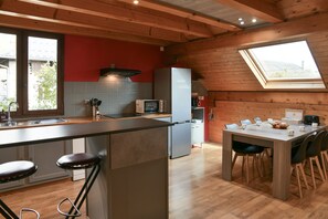Une cuisine moderne dotée d’un îlot central, de tabourets de bar, d’une table à manger avec des chaises et d’une lucarne.