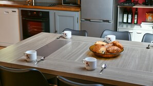 Ein Esstisch mit vier weißen Tassen, einem Croissant-Schälchen und einem Löffel.