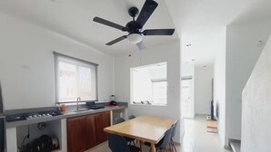 Una cocina moderna con comedor, ventilador de techo y vistas al exterior.