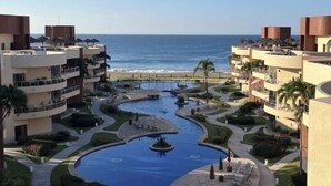 Un complexe hôtelier comprenant plusieurs bâtiments, une piscine centrale et offrant une vue sur la plage.
