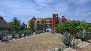 Un complexe hôtelier comprenant un bâtiment principal, des allées pavées et un aménagement paysager de style tropical.